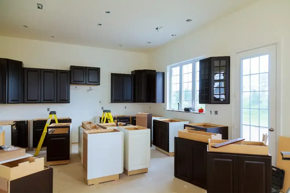 Kitchen under renovation with dark cabinets, white islands, and tools on the floor