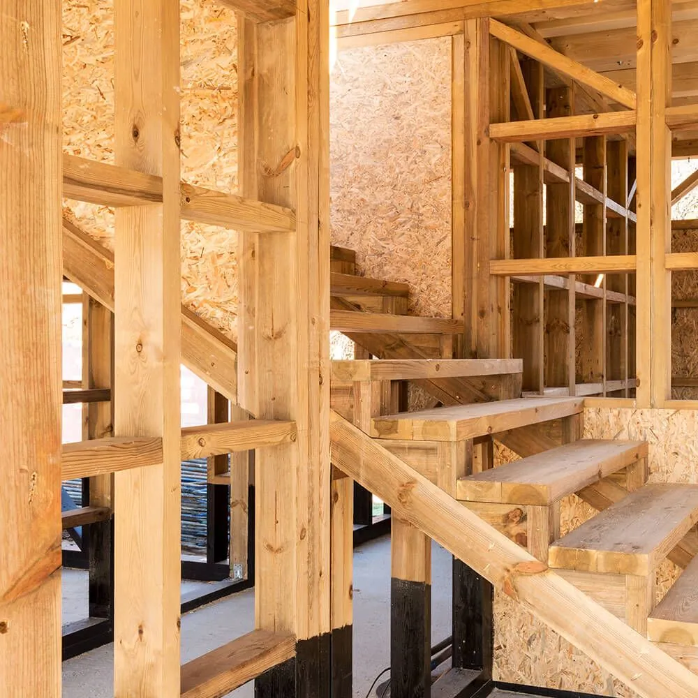 A wooden staircase is being built in a house under construction